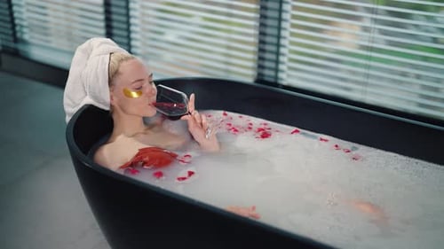 Woman Relax in Milk Bath Drinking Wine Girl Added Eye Patches Resting Lying in Bath with Rose Petals