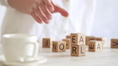 Die Hand einer Frau an einem sonnigen Morgen sammelt den Turm mit dem Wort ZIEL. Motivation zum Ziel. Starke Frau