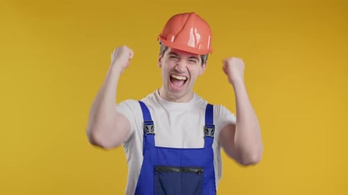 Triumphant Construction Worker Celebrates Against Yellow Background