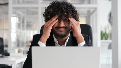 Closeup of Young Indian Man's Face in Office Shows Sign of Work Overload Stress