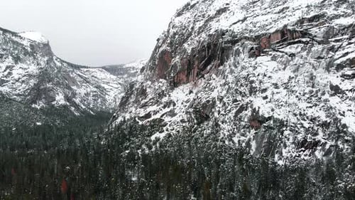 Aerial drone footage flying over Yosemite valley blanketed in snow, surrounded by granite cliffs in