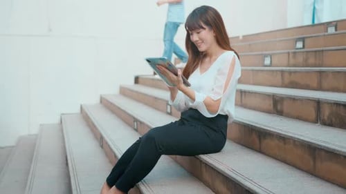 beautiful young asian business woman is using tablet in modern city