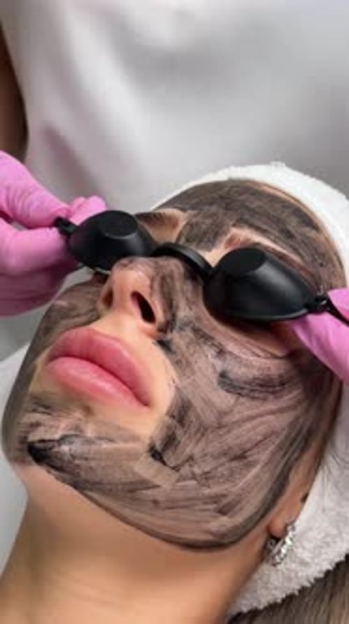 Woman Having Charcoal Facial Mask Treatment at Clinic