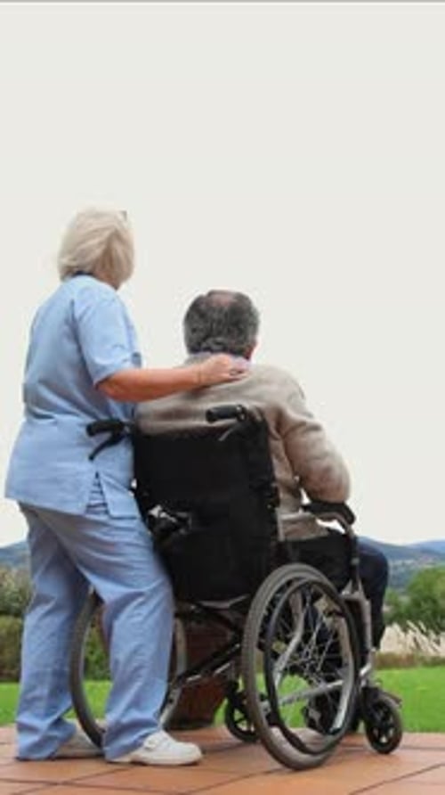 Woman Points with Senior Man in Wheelchair Outside