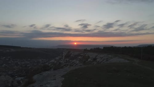 Majestätischer Sonnenuntergang über den felsigen Hügeln und dem Dorf