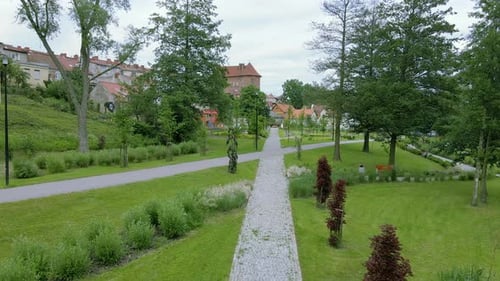 Luftflug über einen Pfad im Park neben einer Wohnanlage an einem bewölkten Tag