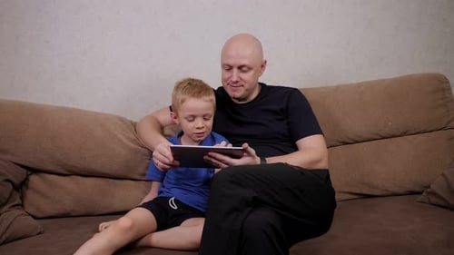 Father and Son Using Tablet Together on Couch