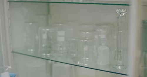 Employé de laboratoire stockant des béchers propres sur une étagère