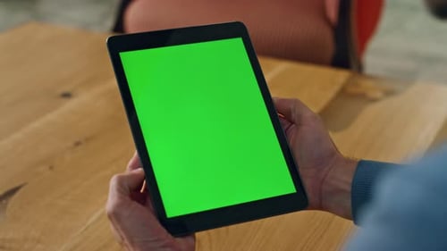 Hands Hold Tablet with Green Screen on Wood