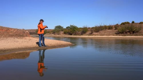 Man Taking Pictures on River Bank on Sunny Day