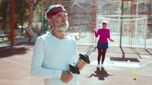 Senior Man Holding Dumbbell, Woman Jumping Rope