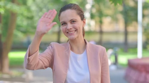 Porträt einer lässigen Geschäftsfrau, die mit der Hand winkt, um im Freien Hallo zu sagen
