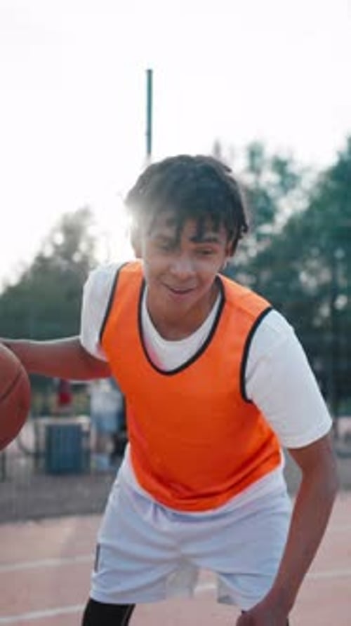 Teen Boy Dribbles Basketball on Outdoor Court