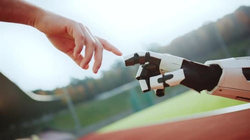 Footage of Robot Hand and Male Hand Pointing Fingertips on Blurred Background of Modern Stadium on