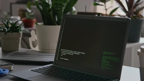 Laptop Displaying Code on Desk with Plants