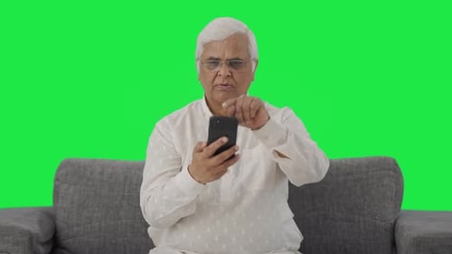 Indian old man scrolling phone Green screen
