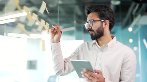 Young creative entrepreneur business man in office uses post papers sticky notes to share idea.
