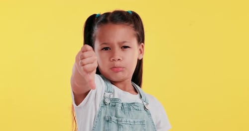 Young girl, sad and thumbs down in face on studio background for frustrated, upset and dislike