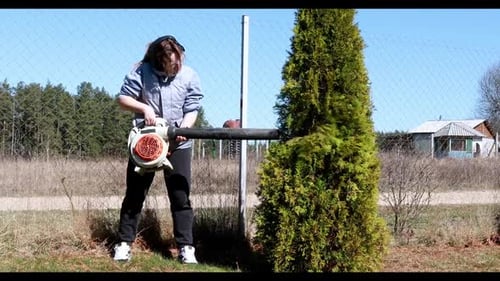 Using a Leaf Blower for Yard Maintenance During Sunny Spring Day in the Countryside