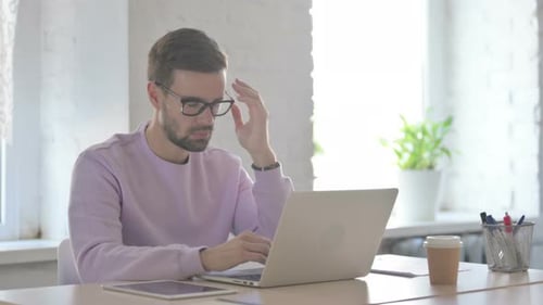 Man Working on Laptop Experiences Headache in Office