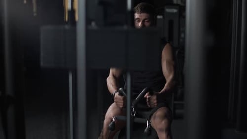 Slow Motion Sporty Man in the Gym Lifting Blocks on Rowing Machine Training on Block Device and Gym