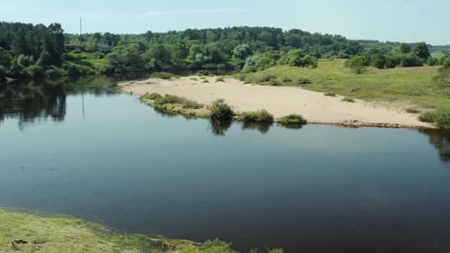 Video from a drone, sunny summer, flight over a river with pine trees along the banks and a sandy be