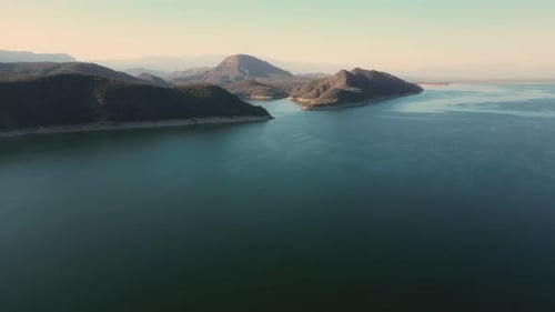 Aerial drone flying over a lake, water dam, with mountains at sunrise. Beautifull dreamy landscape