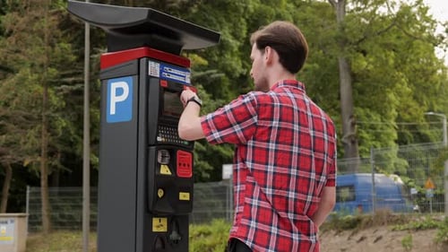 Young Adult Pays at Parking Meter Outdoors