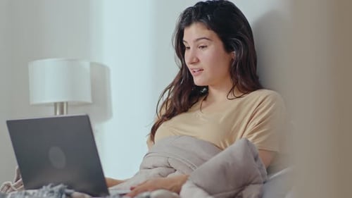 Mädchen macht morgens Videoanruf auf Laptop im Bett