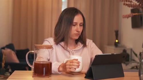 Woman Using Tablet While Drinking Tea at Home
