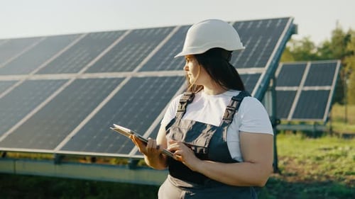 Two Specialists Work at a Power Plant with Solar Panels on a Sunny Day