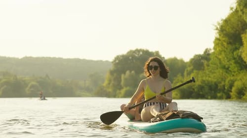 Happy Women Practicing Paddle Boarding Together In River In Summertime Sport Activities