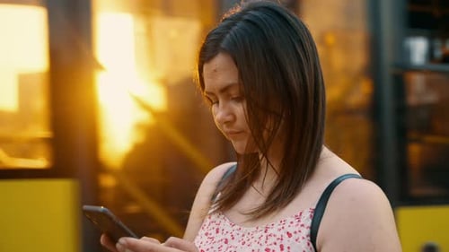 Jeune jolie femme envoie des SMS sur son téléphone intelligent dans la rue de la ville à