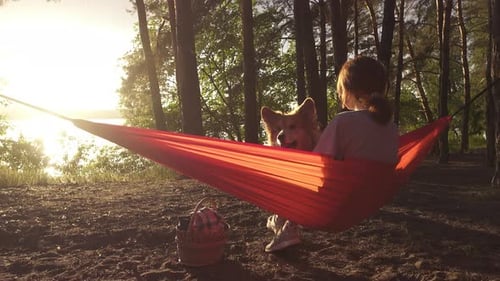 Woman and Dog Relaxing in Hammock at Sunset