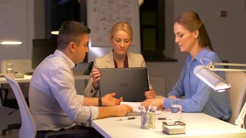Business Team Collaborating on Laptop in Office at Night