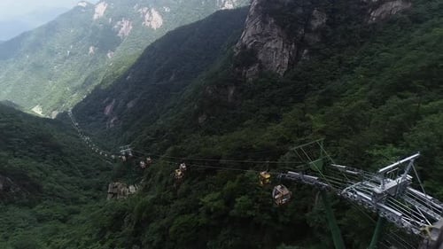 Seilbahnen, die sich zwischen Berggipfeln mit grüner Vegetation bewegen, aus der Vogelperspektive