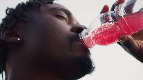 Athletic Man Drinks Refreshing Pink Liquid from Bottle