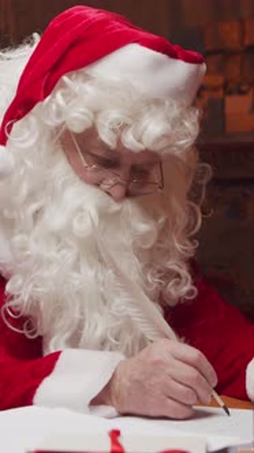 Santa Claus's Workshop Santa is Busy Wrapping a Gift at the Table with a Fireplace and Christmas