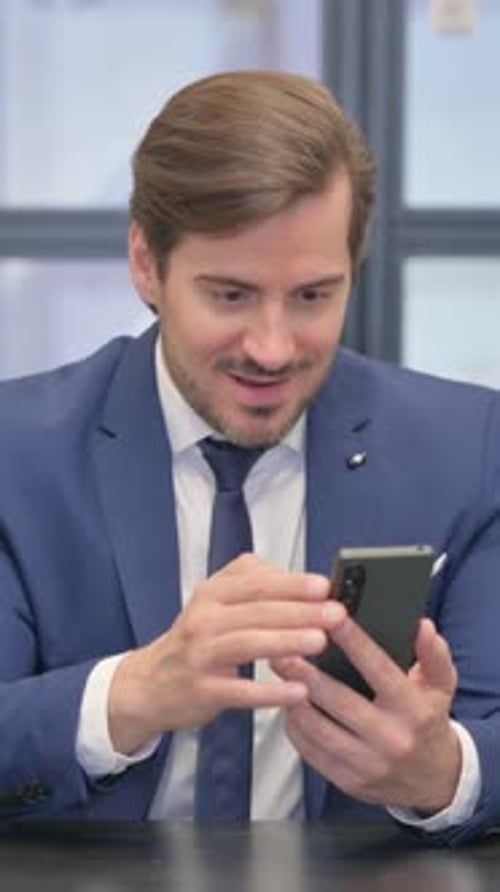 Young Businessman Celebrating Success on Phone, vertical video