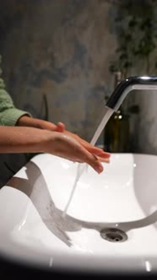 Person Washing Hands at Bathroom Sink