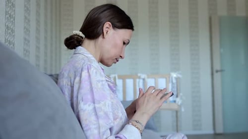 Woman uses phone while sitting on sofa