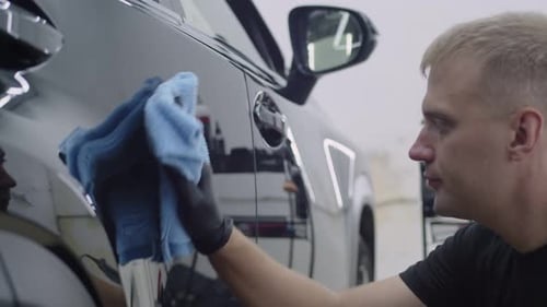 Man Polishing Black Car with Microfiber Cloth