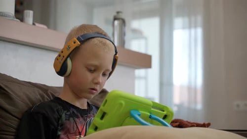 Blond Haired Child Using Tablet Device with Headphones