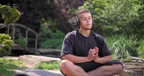Young African American Spirituality Man Meditating Yoga Asana Sitting in a Park Outdoor and