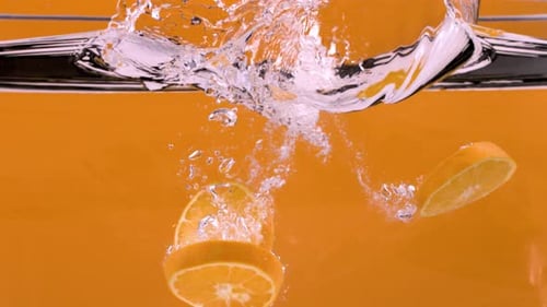 Superzeitlupenaufnahme von Orangenscheiben, die ins Wasser fallen, 1000 Bilder pro Sekunde