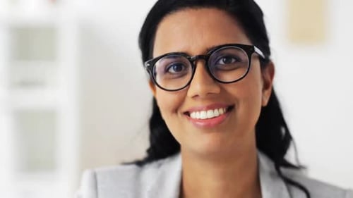 Smiling Woman Wearing Glasses in Office Environment