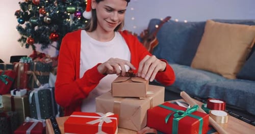 Woman Tying Ribbon on Christmas Gift