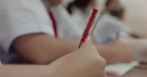 Foto gravada enquanto os estudantes em uniformes brancos escrevem as respostas em seus papéis