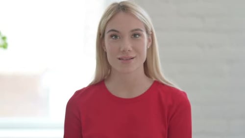 Smiling Young Woman Waving and Talking to Camera