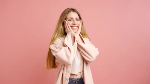 Surprised Young Woman Posing in Front of Pink Backdrop